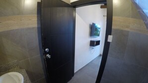A bathroom with a black door, a white sink, a toilet, and a shower area.