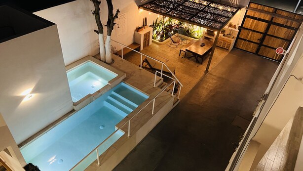 A modern indoor pool area with two pools, a seating area with a table and chairs, and a staircase leading to another level. - Casa Palo Verde  (Cabo San Lucas)