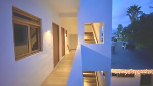 A modern house with a wooden staircase, a hallway with a door, and a view of the outside. - Casa Palo Verde  (Cabo San Lucas)