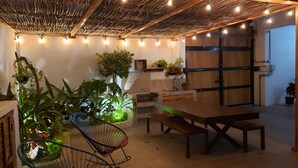 A cozy indoor space with a wooden table and chairs, surrounded by potted plants and string lights. - Casa Palo Verde  (Cabo San Lucas)