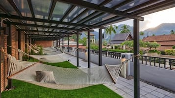 A covered outdoor area with two hammocks and artificial grass.