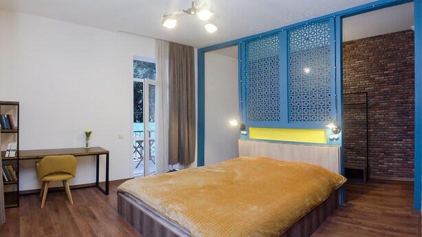 Un dormitorio con cama, escritorio, silla y estantería.