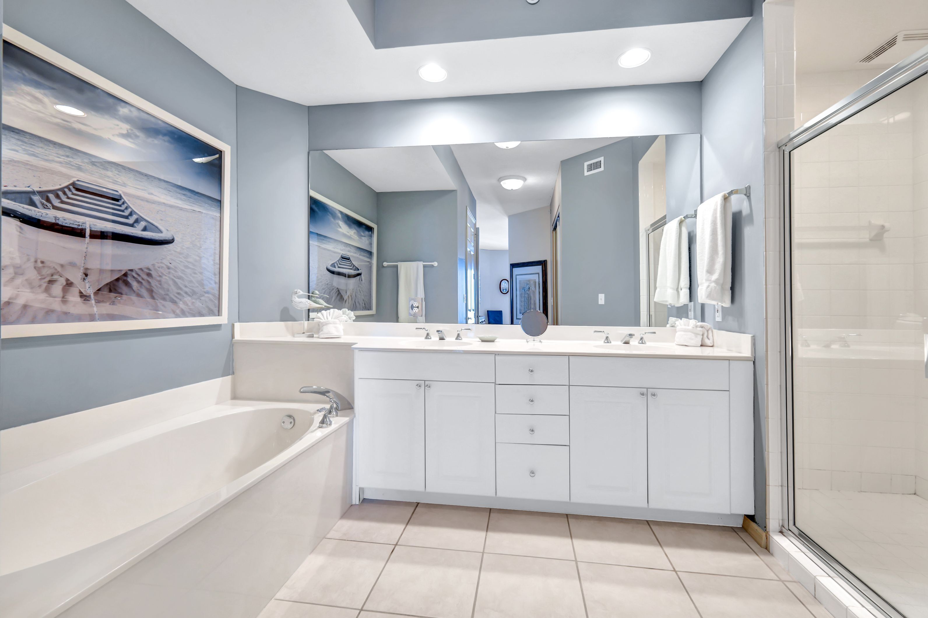 A modern bathroom with a large bathtub, a double vanity with a mirror, and a glass shower enclosure.