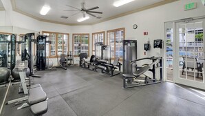 A gym with various exercise equipment, large windows, and an exit sign. - Regatta - Enjoy Gulf Views, Walk to the Beach! (Naples)