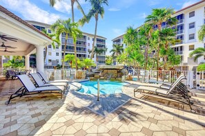 Relax by the resort pool surrounded by palm trees and tropical plants.