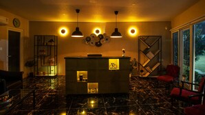 A lobby with a reception desk, seating area, and a large window. - The G Snoozebox (Udaipur)