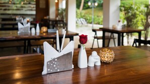 A restaurant with wooden tables and hanging pendant lights. - Le Candles Resort (Kozhikode)