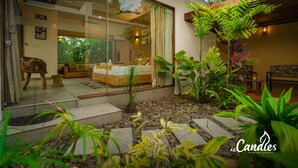 A modern resort room with a glass door, a bed, and a small seating area. - Le Candles Resort (Kozhikode)