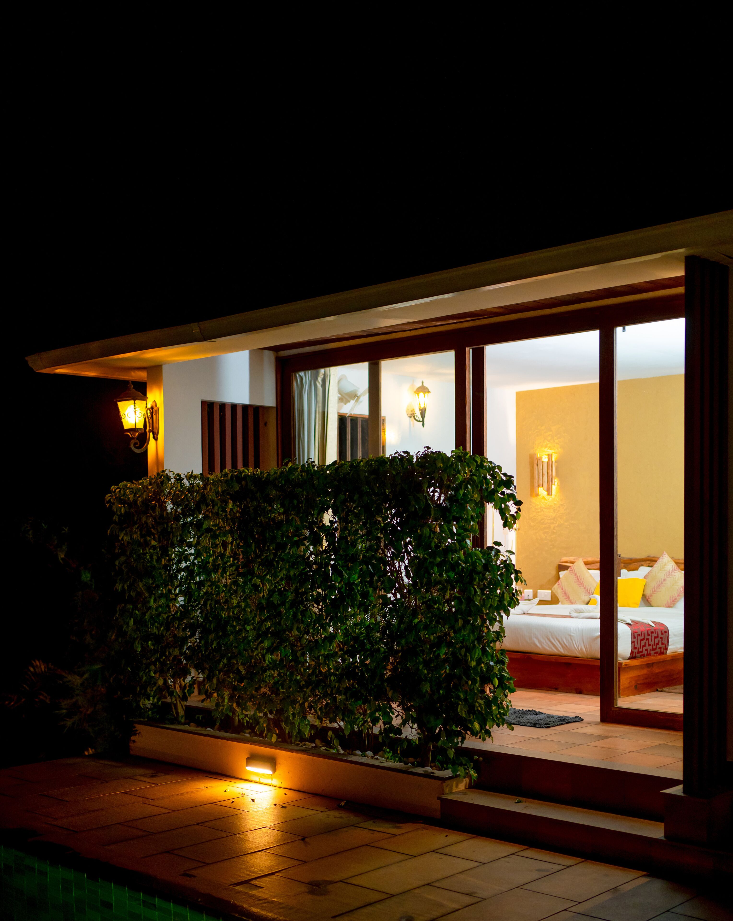 A modern hotel room with a large bed, a nightstand, and a window with curtains.
