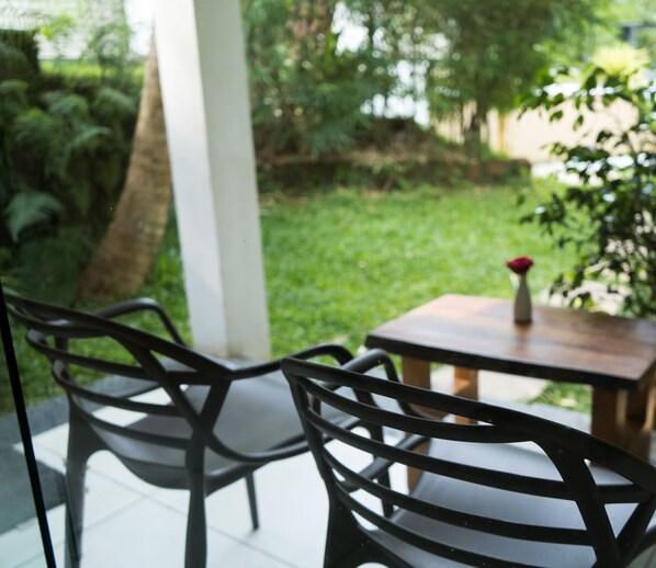 A patio with two metal chairs and a small table with a vase of flowers.
