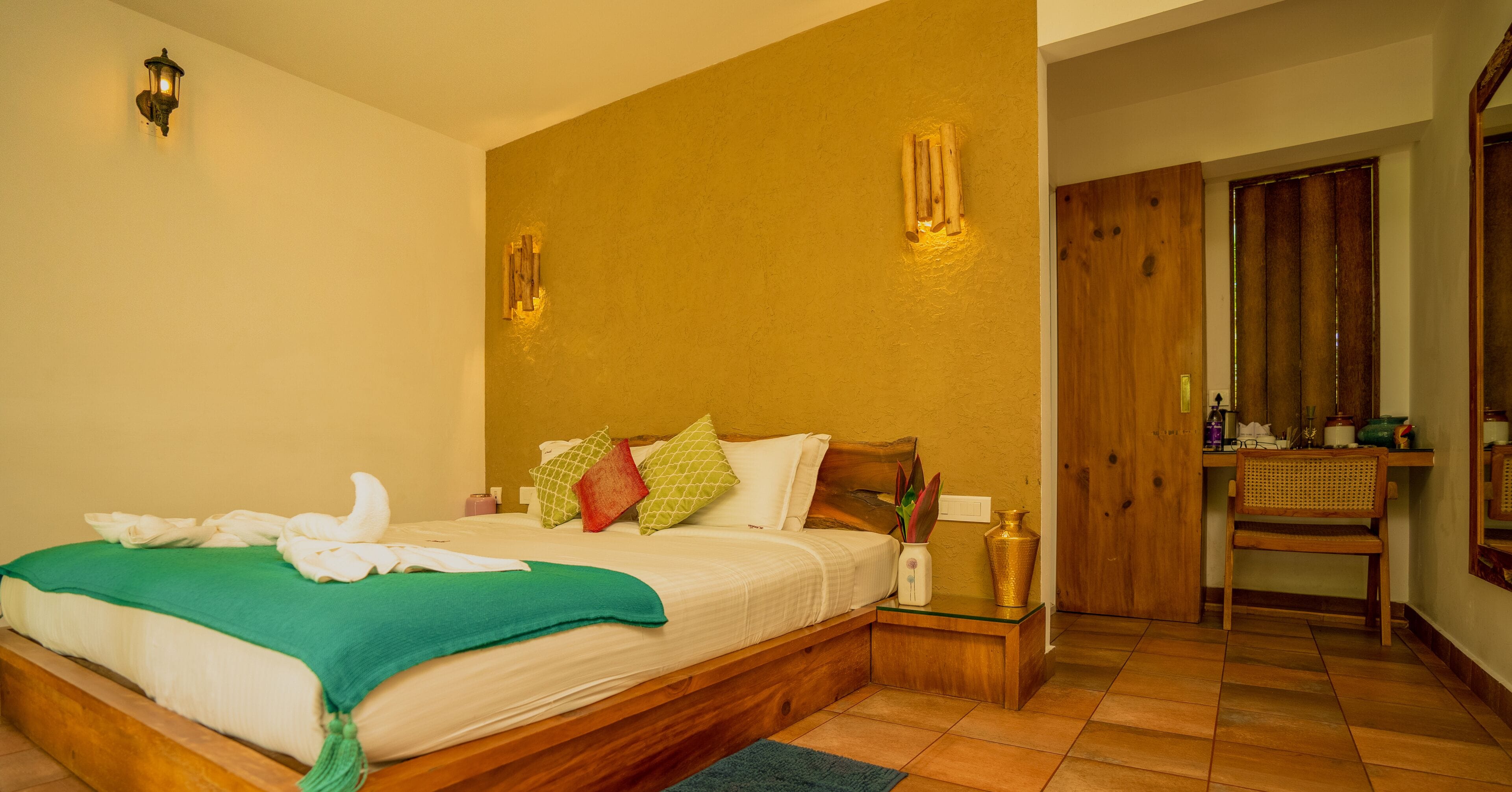 A bedroom with a wooden bed, a nightstand, a mirror, and a wooden door.
