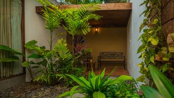 Un jardín con un banco, diversas plantas y un sendero de piedra.