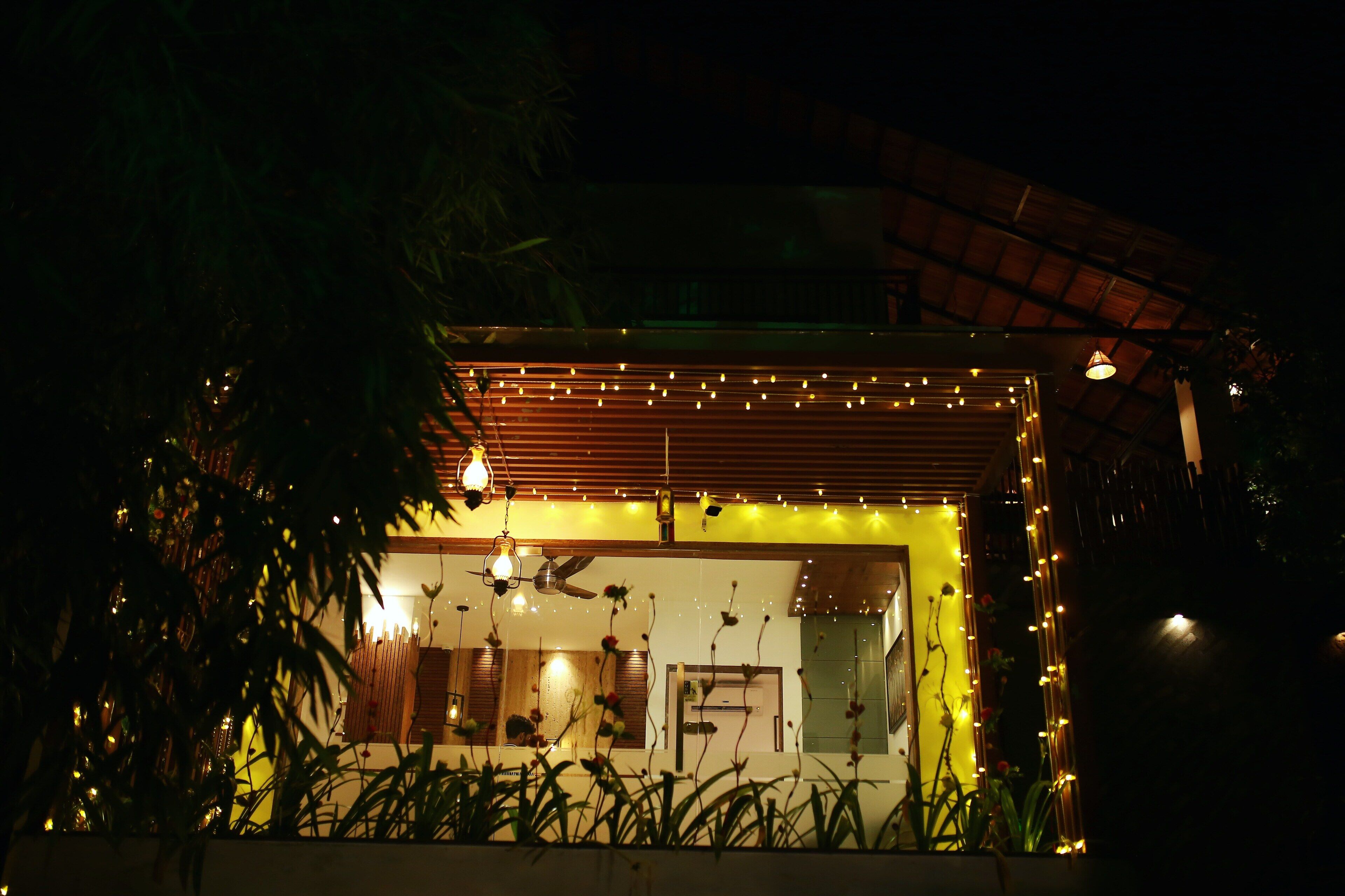A modern house with a covered porch, string lights, and a visible window.