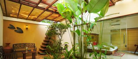 A wooden staircase leading to a bedroom with a glass door, surrounded by lush green plants.