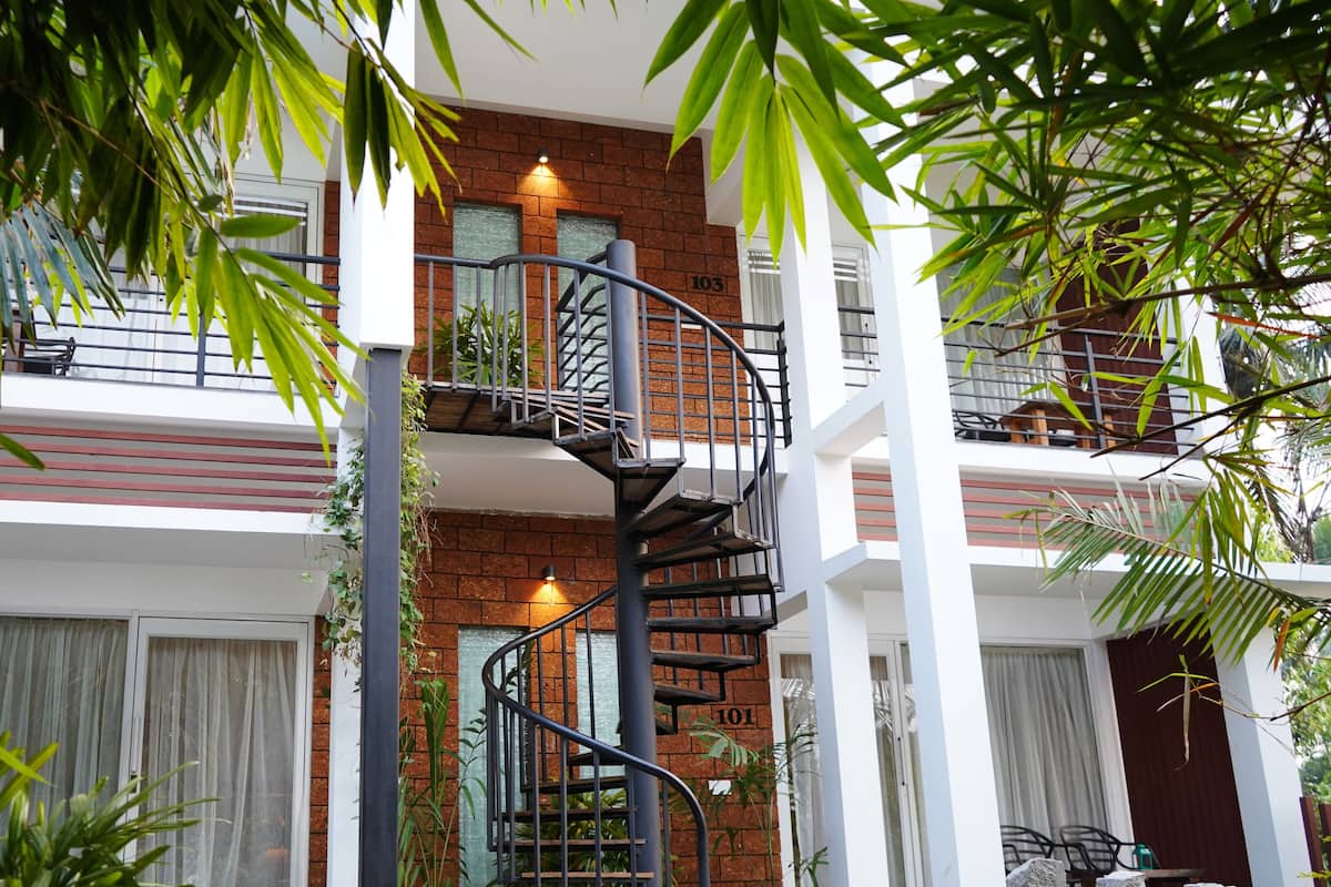 A multi-story building with a spiral staircase, balconies, and potted plants.