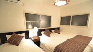 A hotel room with two beds, a nightstand with a lamp, and windows with blinds. - Dekijima Sakura House (Osaka)