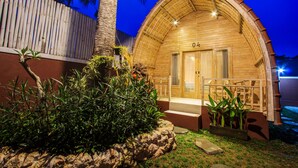 A wooden structure with a curved roof, a door, and a small porch area. - Puri Lumbung Village (Carangsari)
