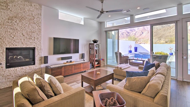 A spacious living room with a flat-screen TV mounted on a textured wall, a ceiling fan, and a large sliding glass door leading to an outdoor area. - 068332: 'Desert Pearl' 3 BR Oasis w/ Private Pool! (La Quinta)