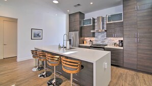 A modern kitchen with a central island, bar stools, stainless steel appliances, and dark wood cabinetry. - 068332: 'Desert Pearl' 3 BR Oasis w/ Private Pool! (La Quinta)