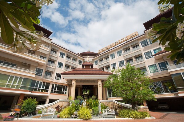 A multi-story hotel with a central atrium, balconies, and a garden area with plants and a bench. - Kwanruen Park hotel (Nakhon Ratchasima)
