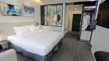 A modern hotel room with a large bed, a bedside table, a mirror, and a walk-in closet.