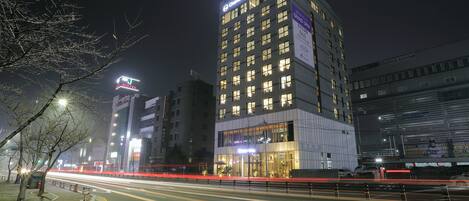 Un hôtel à plusieurs étages, doté d’une enseigne lumineuse, d’une entrée bien éclairée et d’une architecture moderne.