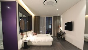 Een moderne hotelkamer met een groot bed, een bureau en een televisie.