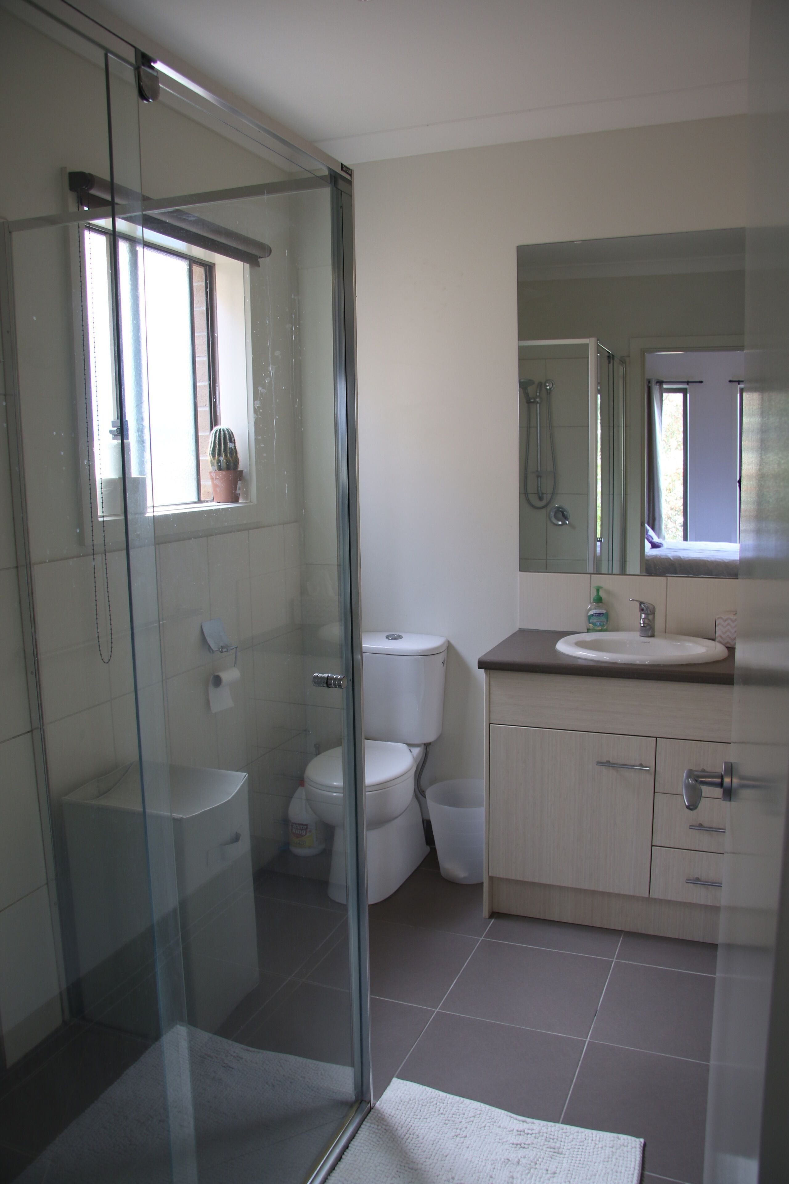 Un bagno moderno con box doccia in vetro, un water, un lavandino e uno specchio sopra il lavandino.