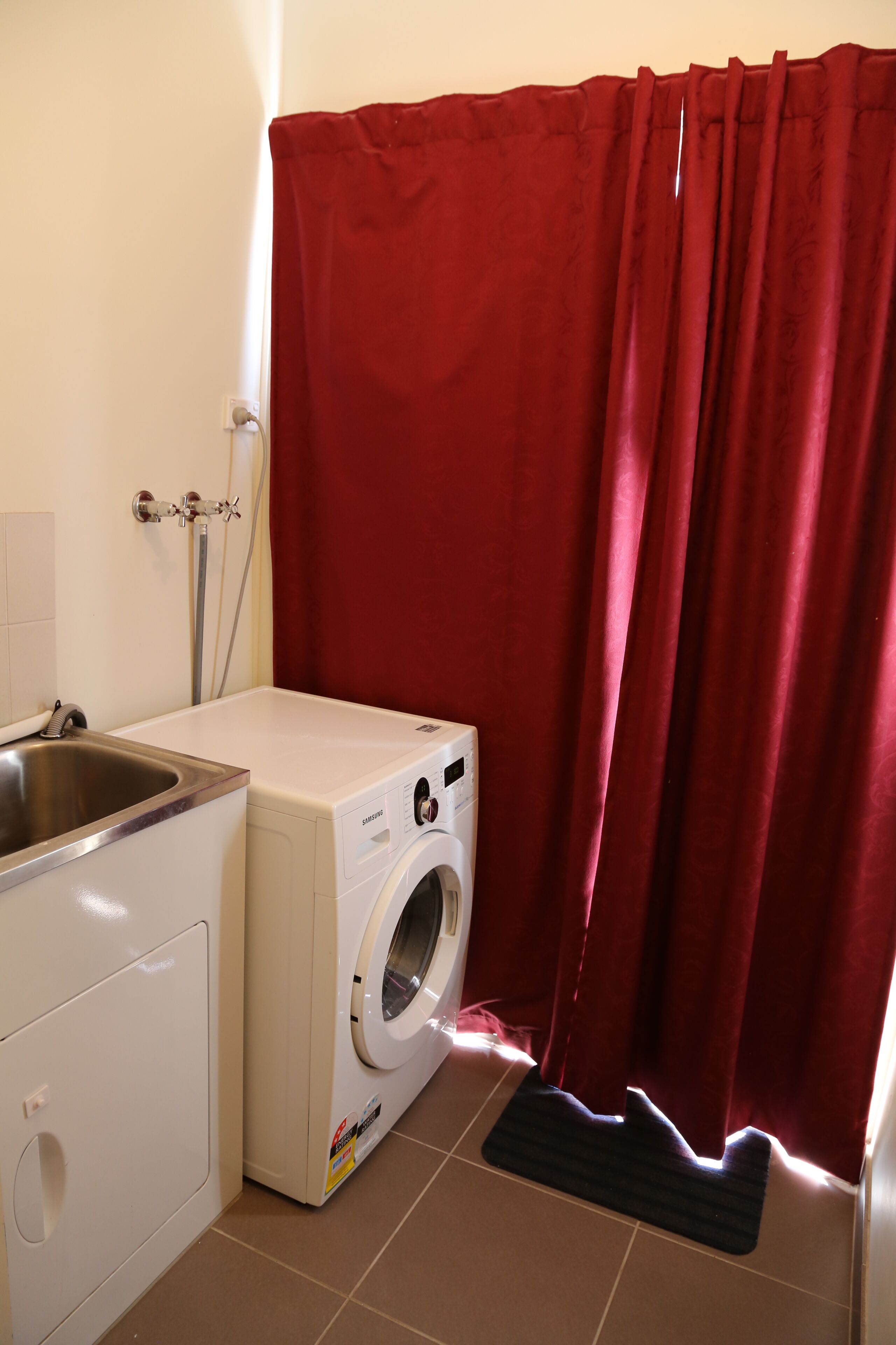 A compact laundry area with a washing machine, a sink, and a shower curtain.