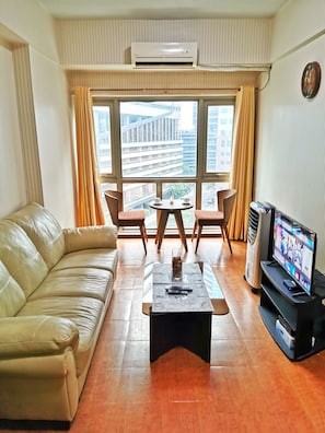Relax in this stylish living room with a comfortable sofa, coffee table, and large window offering a city view.