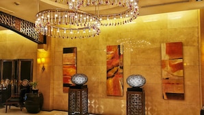 A lobby with a grand chandelier, abstract wall art, and a staircase. - Forbeswood Parklane (Taguig)