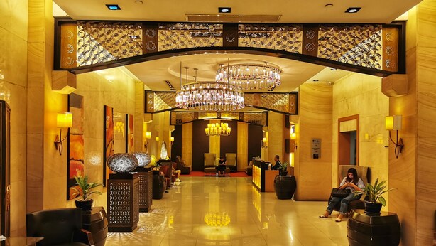 A spacious lobby with a high ceiling, a grand chandelier, and a reception desk. - Forbeswood Parklane (Taguig)