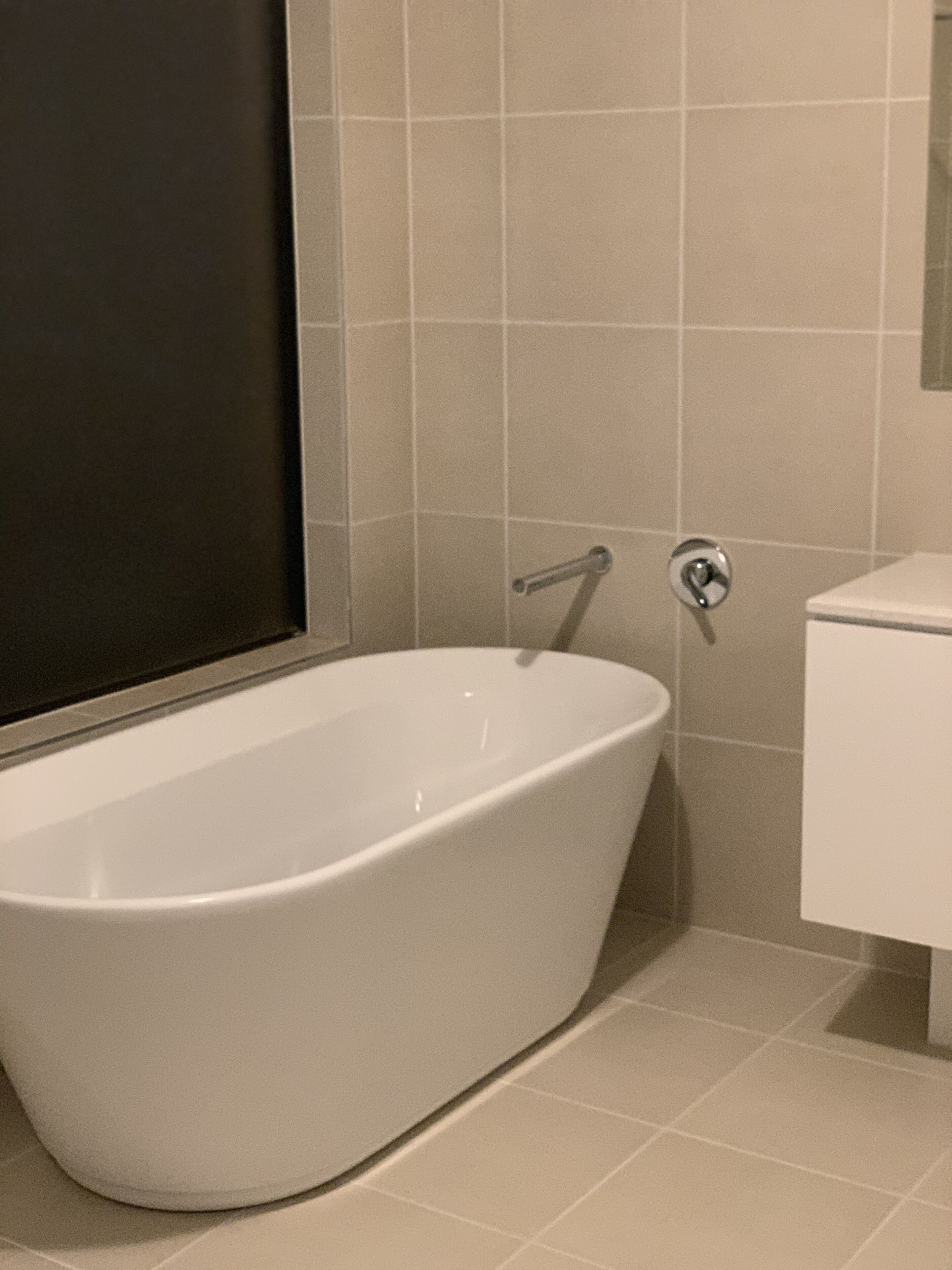 A modern bathroom with a freestanding bathtub, a toilet, and a wall-mounted sink.