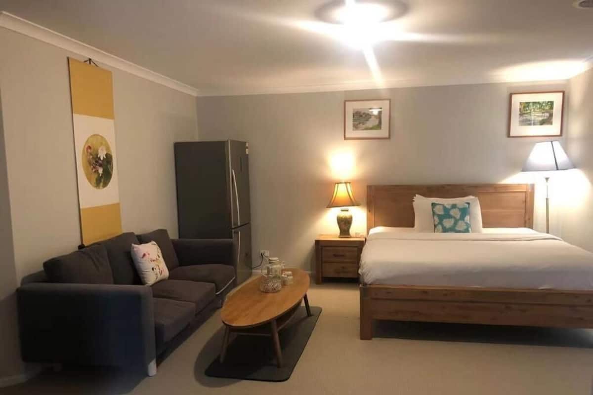 Une chambre à coucher comprenant un lit, un canapé, une table et un réfrigérateur.