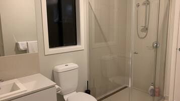 A bathroom with a toilet, sink, and glass-enclosed shower.