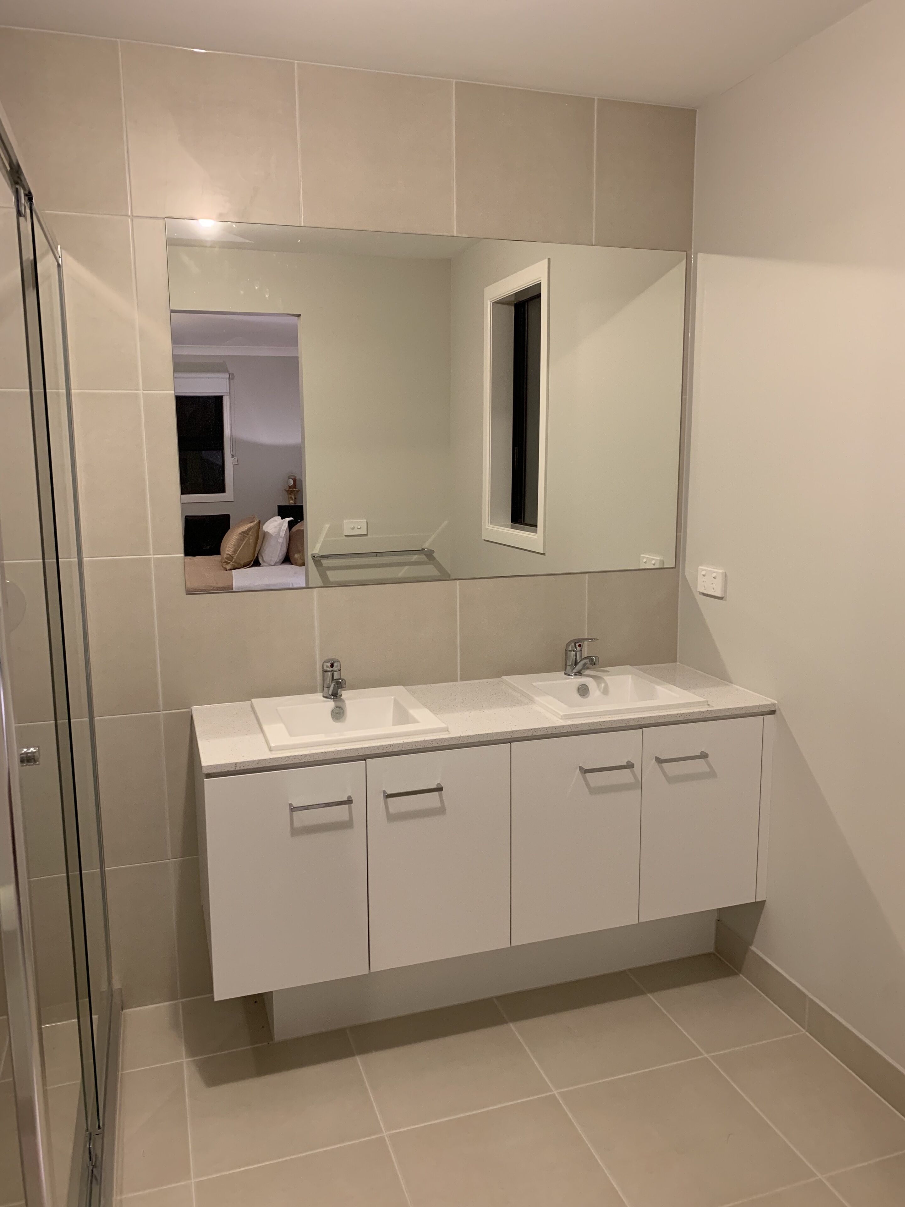 Ein modernes Badezimmer mit zwei Waschbecken, einem großen Spiegel und einer Duschkabine.
