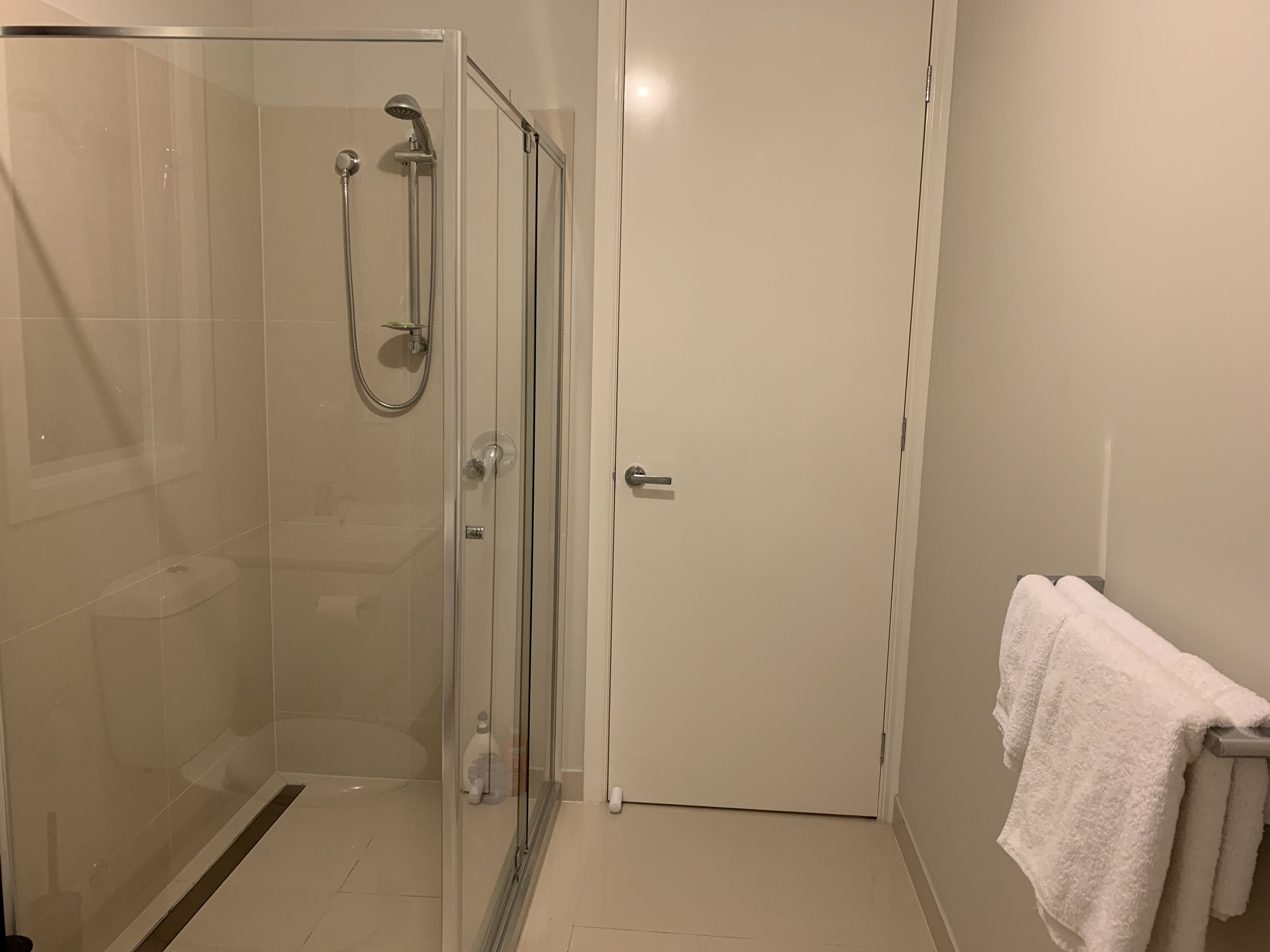 Ein modernes Badezimmer mit einer Glaskabine zur Dusche, einer Toilette und einem Handtuchhalter.