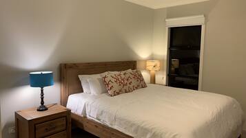 Un lit bien fait, avec une literie blanche et une tête de lit en bois, une table de chevet avec une lampe et une armoire avec un miroir.
