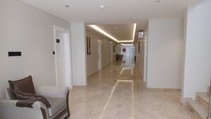 A spacious hallway with a marble floor, a sofa with a brown cushion, and a staircase on the right. - Raoum Inn Serviced Apartments-Shaqraa (Shaqra)