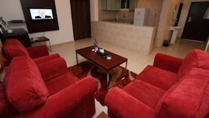 A living room with red sofas, a coffee table, and a TV on the wall. - Raoum Inn Serviced Apartments-Majmaa (Al Majmaah)