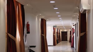 A hotel corridor with a polished floor, red curtains, and recessed lighting. - Raoum Inn Serviced Apartments-Majmaa (Al Majmaah)