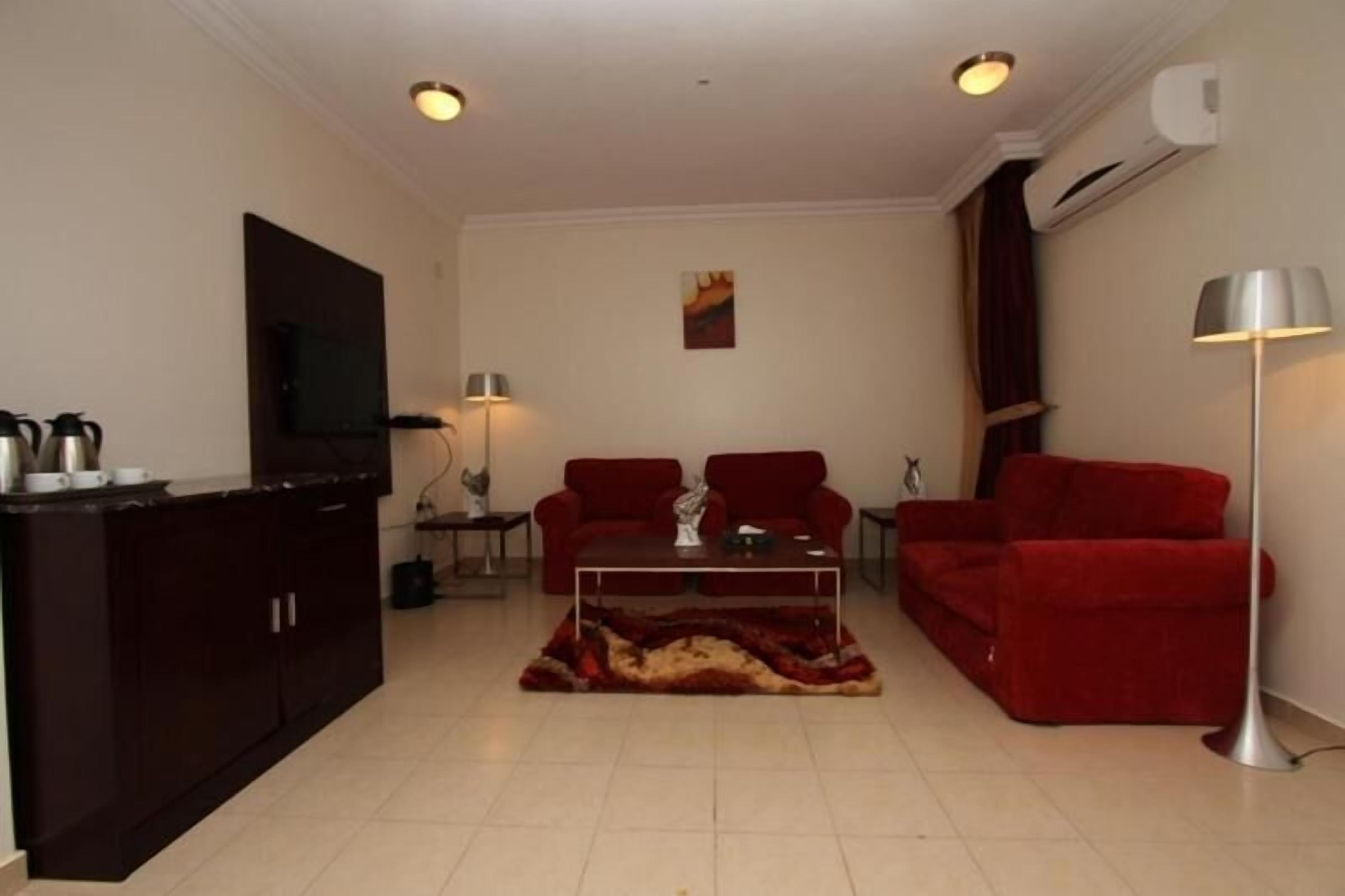 A living room with a dark wooden cabinet, a red sofa set, a coffee table, and a floor lamp.