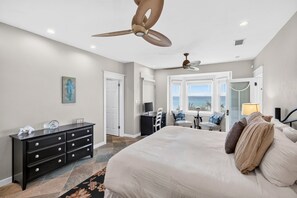 A bedroom with a large bed, a dresser, a desk, a chair, a ceiling fan, and a window with a view. - The Point - Oceanfront Home in Blue Mountain Beach with Direct Beach Access (Santa Rosa Beach)