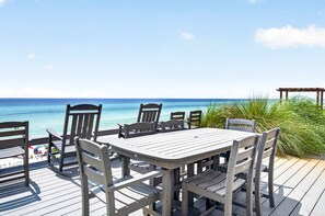 A wooden deck with a table and chairs overlooking a beach. - The Point - Oceanfront Home in Blue Mountain Beach with Direct Beach Access (Santa Rosa Beach)