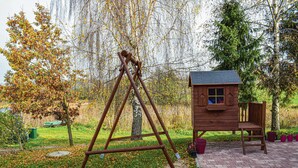 Un portique en bois et une petite maison de jeu en bois dans un jardin.