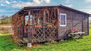 Une cabane en bois rustique, dotée d’un porche en bois, d’une fenêtre et d’une table de pique-nique.