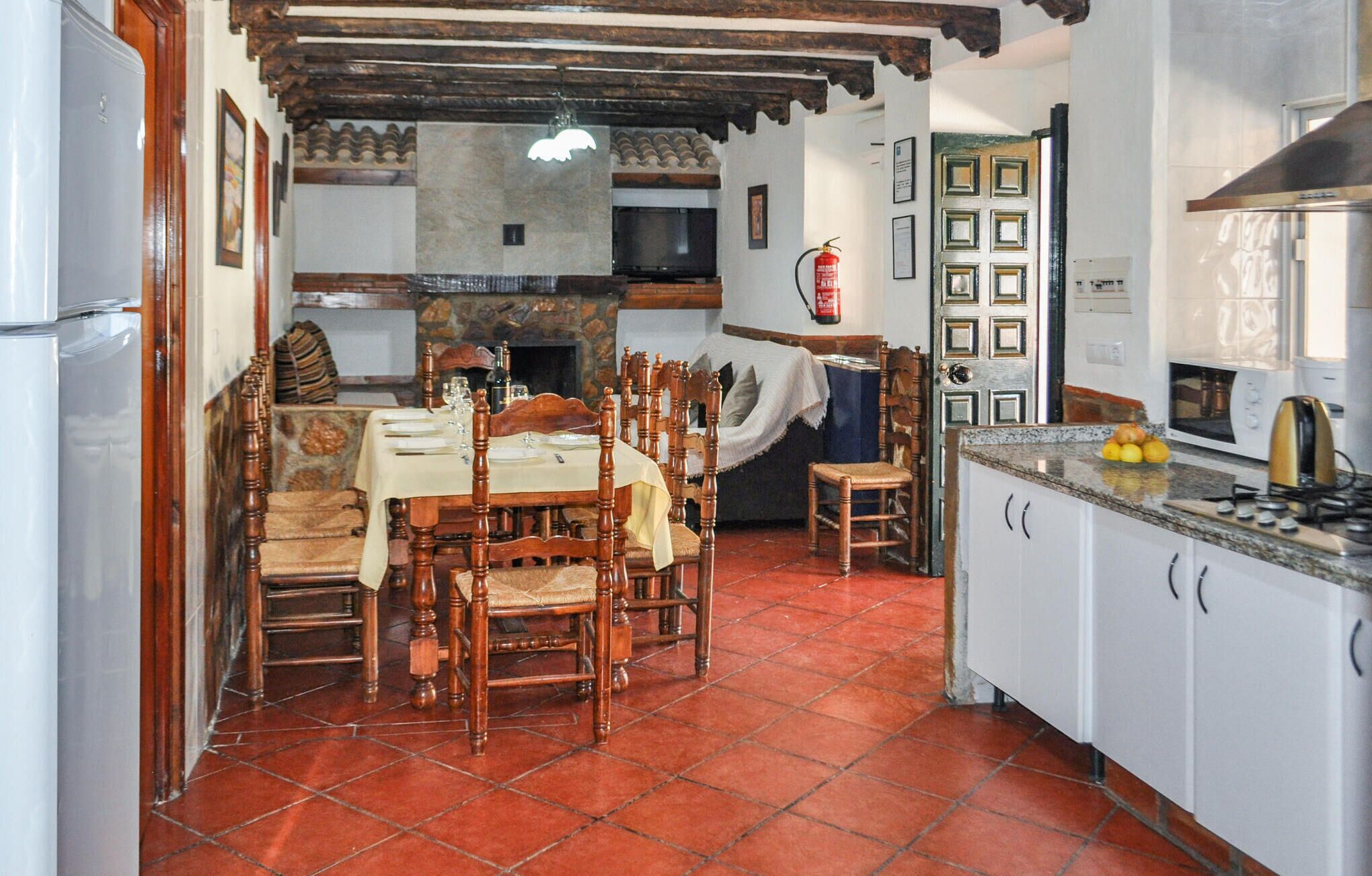 A kitchen with a dining area, featuring wooden chairs, a tiled floor, and a stove.