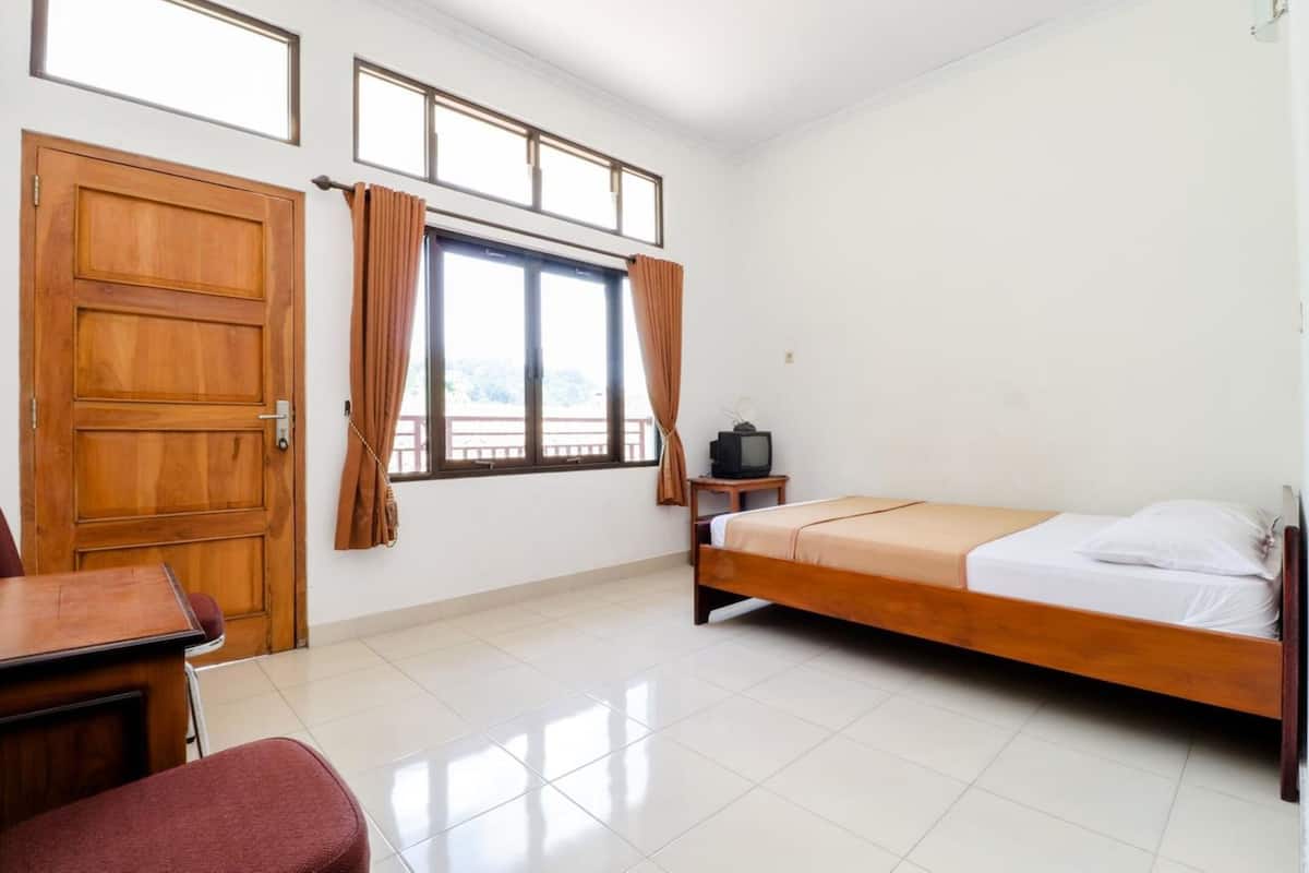 A room with a wooden door, a window with curtains, a bed, a TV on a small table, and a chair.