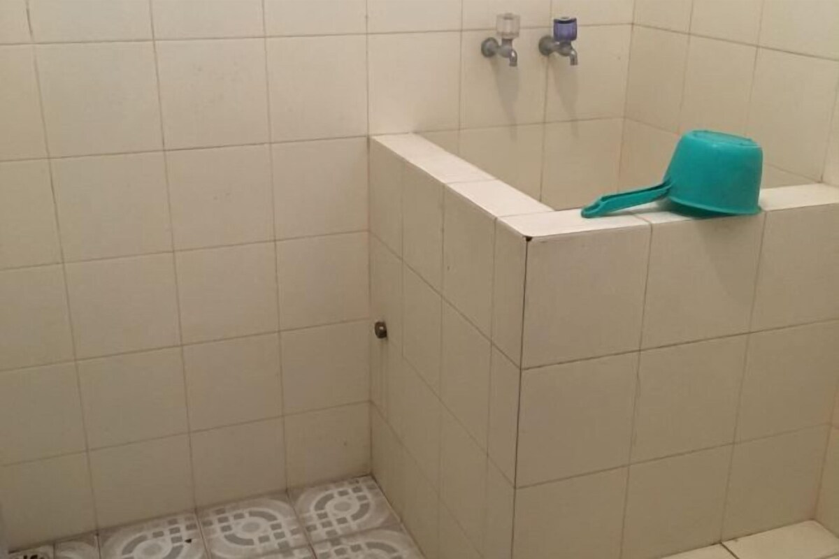 Une salle de bain avec des carreaux blancs, une baignoire et un pommeau de douche bleu.