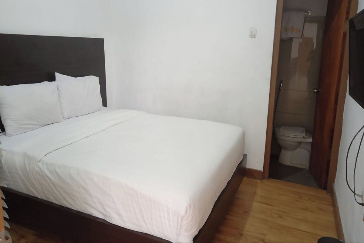 Ein Schlafzimmer mit einem Bett, einem Holz-Kopfteil und einer weißen Wand.